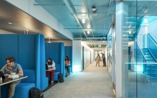 People sitting a blue booth areas with a staircase on the right side of the image. 