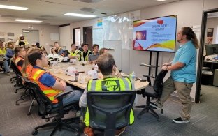 Group of people sitting a table listening to a presentation