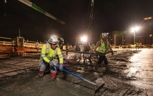 Group of people working on a concrete pour at night