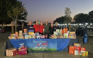 Group of people standing with donated supplies during a community supply drive. 