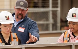 Two people learning from someone else during a Construction 101 event. 