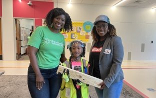 Two adults standing with a child learning about construction