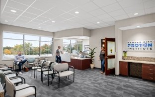 A waiting room with a person checking in and another person sitting in a chair.