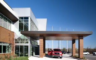 An exterior view of the drive-through drop off area at the entrance of the KC Proton Institute building.