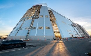 Exterior view of one side of the hangar under construction with the sun shining through it