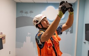 A person wearing PPE taking a photo in a hospital room