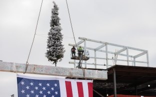 The final beam with a tree being hoisted to the top of the structure