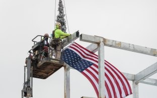 Two people adding the final beam to the top of the structure