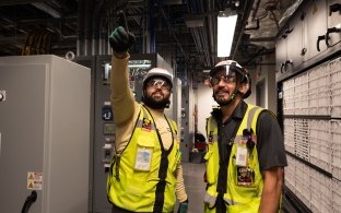 Two people wearing PPE and pointing