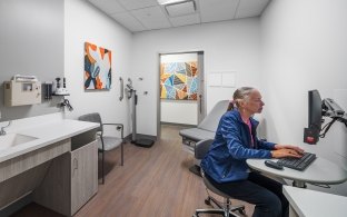 A person working on a computer inside a patient exam room