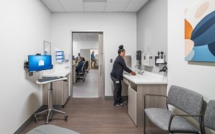 A person washing their hands at a sink in a patient exam room