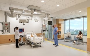 People standing around a bed in a patient room in the PICU