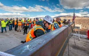 Construction workers prepare steel beam.