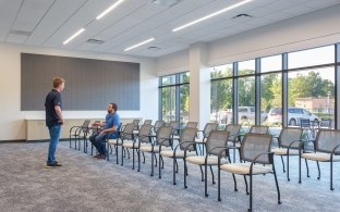 A person sitting in a chair talking to a person who is standing