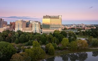 Twilight aerial view of Barnes-Jewish Hospital campus rising above a tree-filled park and lake.