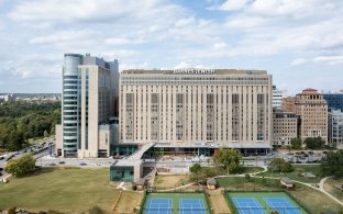 Daytime aerial view of Barnes-Jewish Hospital tower facing a park with tennis courts