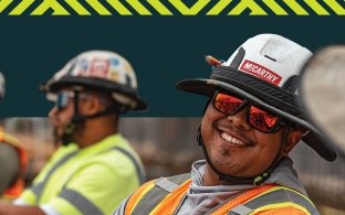 A person wearing PPE and smiling at another person.