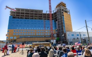 A group of people seated outside the hospital under construction