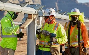 Three people working on the structure that will hold solar panels