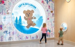 Two children looking at a sign that says "Let's Discover"