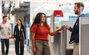 People standing and talking near a desk