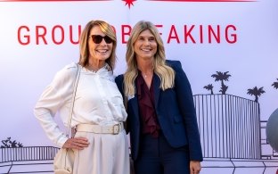 Two people posing in front of a groundbreaking backdrop