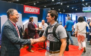 Two people shaking hands with the McCarthy booth in the background