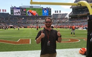 A McCarthy employee gives two thumbs up on the field at a Denver Broncos game before kickoff.