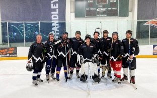 	Ten members of the McCarthy ice hockey team pose together on the rink in matching black jerseys.
