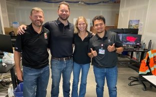 Four McCarthy team members smile together in an unfinished office space on the jobsite.