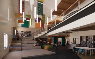 An interior space in a school with a wide staircase and tables and chairs.