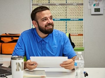 A person sitting at his desk smiling.