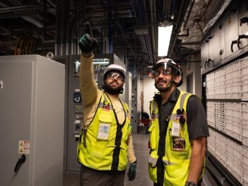 Two people wearing PPE and pointing