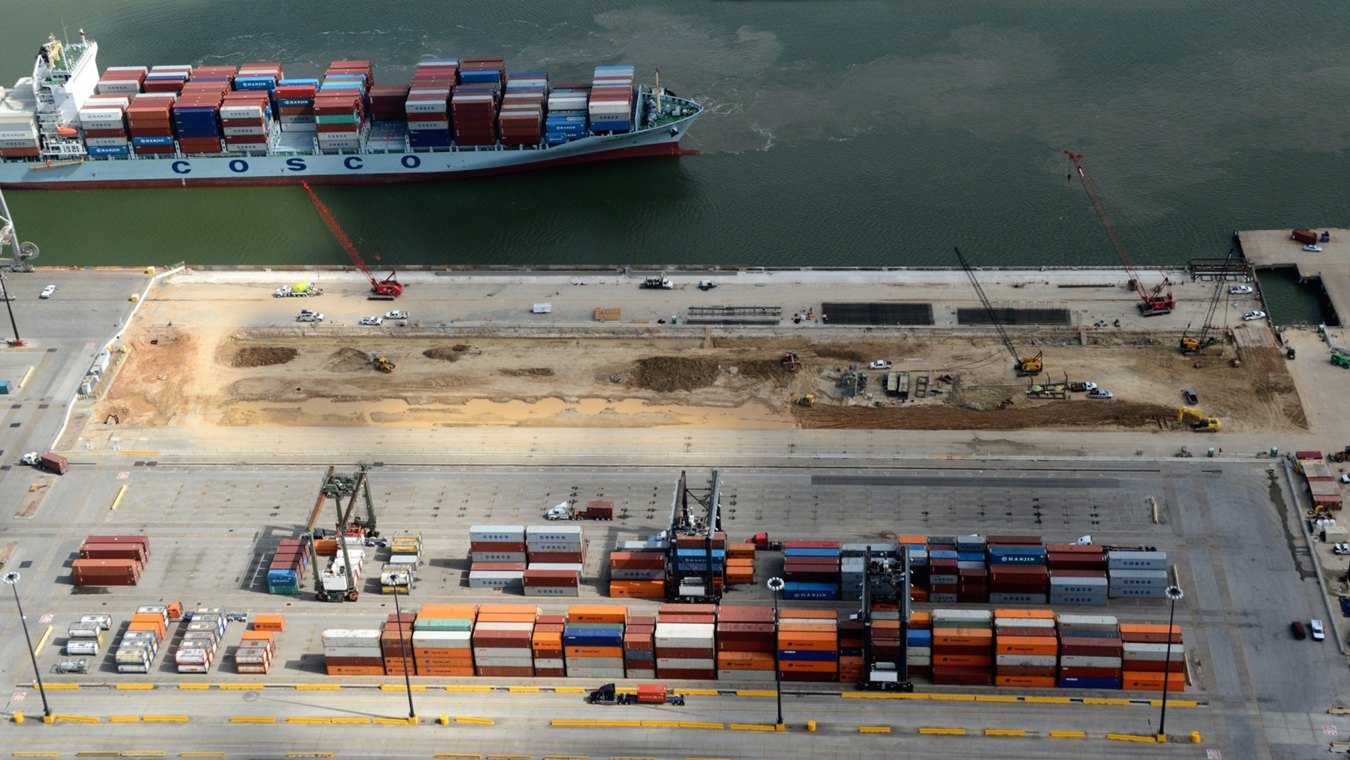 Aerial view of the site during construction with a ship on the water in the background