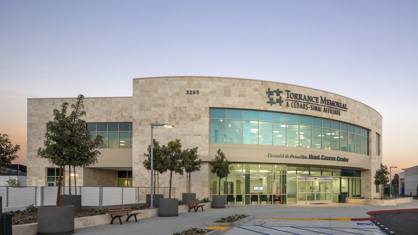 Entrance and front of the cancer center structure that features a blue sky and trees