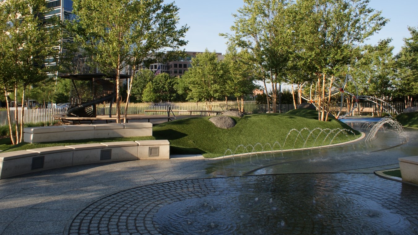 A fountain, bench, and greenery area at the park