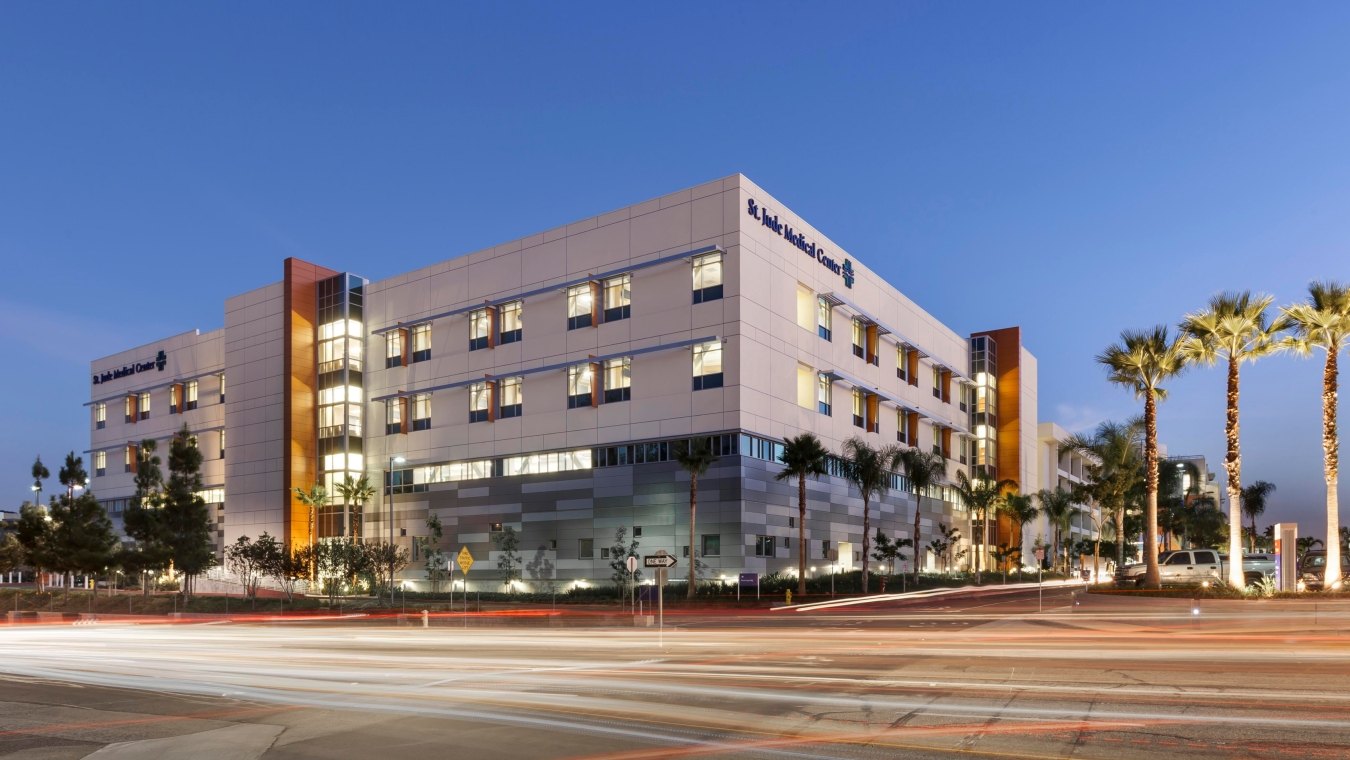 Outdoor image of the entire medical center with parking and palm trees