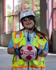 A person wearing PPE and holding a soccer ball.