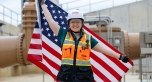 A person wearing PPE and holding a U.S. Flag behind themselves.