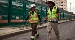 Two people wearing PPE and walking on a jobsite