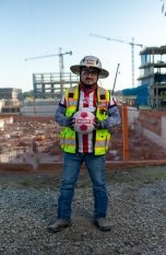 A person on a jobsite wearing PPE and holding a soccer ball