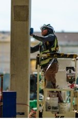 A person wearing PPE and working on a concrete column