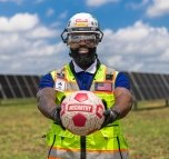 A person on a jobsite wearing PPE and holding a soccer ball.