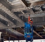 A person wearing PPE standing on a piece of equipment 