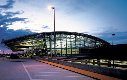 Outdoor image of a terminal thats completely glass and steal with clouds in the sky