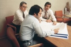 Three people sitting at a desk looking at site plans.