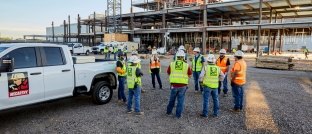 Construction workers standing in a circle at a jobsite.