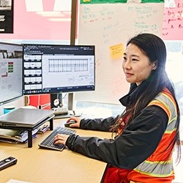 A person sitting at a desk and looking at two computer monitors