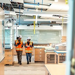 Two people walking through a research lab under construction
