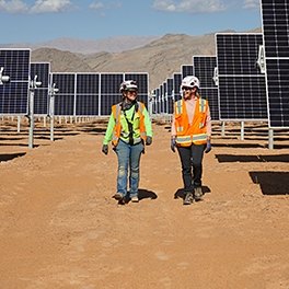 two people walking beside solar panels in the desert